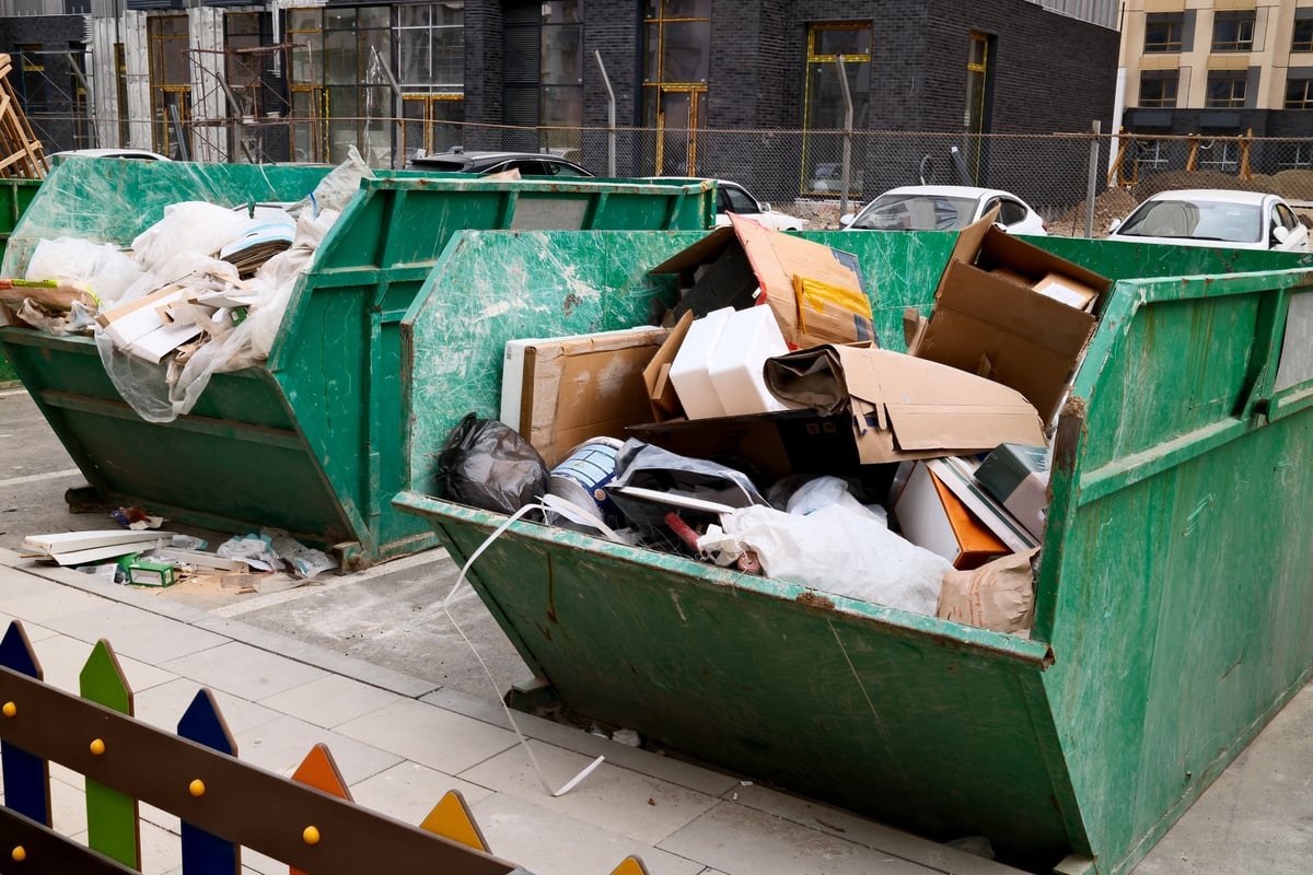 Overflowing dumpster filled with debris, cardboard, and construction waste from property cleanup